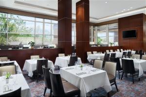 林夕昆高地巴尔的摩华盛顿机场威斯汀酒店 - BWI的餐厅设有白色的桌椅和窗户。
