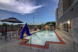 休斯顿TownePlace Suites by Marriott Houston Hobby Airport的一个带蓝伞的游泳池和一座建筑