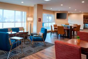 大急流城TownePlace Suites by Marriott Grand Rapids Airport的一间设有桌椅和电视的等候室