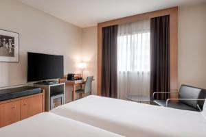 塞维利亚AC Hotel Sevilla Fórum by Marriott的配有一张床和一台平面电视的酒店客房