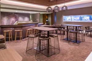 FriendshipSpringHill Suites by Marriott Greensboro Airport的餐厅内带桌子和凳子的酒吧