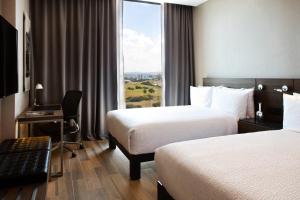 克雷塔罗克雷塔安铁亚万豪AC酒店的酒店客房设有两张床、一张书桌和一个窗户。
