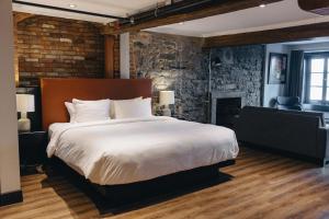 蒙特利尔Lofts du Vieux-Port by Gray Collection的一间卧室设有一张大床和砖墙