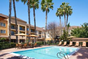 米尔皮塔斯米尔皮塔斯硅谷万怡酒店的一个带桌椅的游泳池,棕榈树