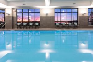 梅普尔格罗夫SpringHill Suites Minneapolis Maple Grove/Arbor Lakes的大楼内带桌椅的游泳池