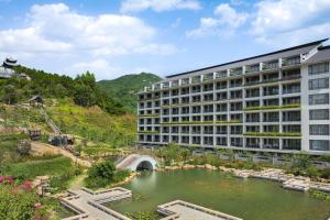 茂名茂名喜来登温泉度假酒店的山前带池塘的建筑