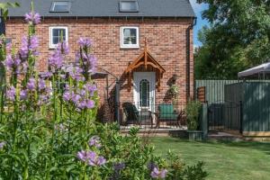 CranwellLuxury retreat in Lincolnshire with hot tub的院子里布满紫色花的砖房