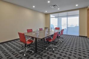舍伍德帕克TownePlace Suites by Marriott Edmonton Sherwood Park的一间会议室,配有长桌子和红色椅子