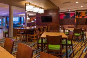 马里兰高地Fairfield Inn & Suites by Marriott St. Louis Westport的一间带桌椅和电视的用餐室