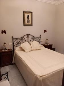 博尔穆霍斯Al ladito de Sevilla的一间卧室配有一张带2个床头柜的大型白色床