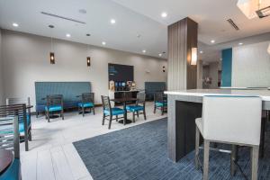 休斯顿Holiday Inn Express & Suites Houston - Hobby Airport Area, an IHG Hotel的大堂设有桌椅和酒吧。