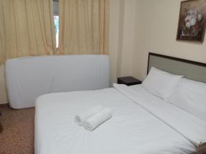 卢穆特Apartment Teluk Batik的卧室配有白色的床和毛巾