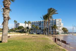 拉皮内达Just Oliver Holidays - Paradis Playa Seafront的一座公园,在一座建筑前有长椅和棕榈树
