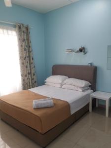 彭亨Haji Homestay - A tiny house with 2 bedrooms的卧室内的一张床铺,卧室内有蓝色的墙壁
