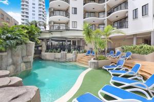 穆卢拉巴2 Bedroom Central Mooloolaba Resort with Pool, Spa, Mini Golf的一座带蓝色椅子的游泳池和一座建筑