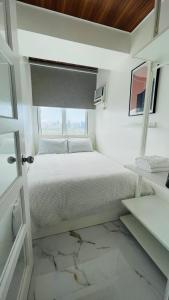 马尼拉San Lorenzo Place的白色的卧室设有床和窗户