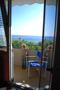 瓦拉泽皇宫酒店的两个孩子站在一个眺望着大海的阳台