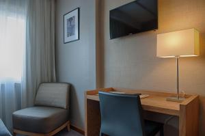 科英布拉奥斯陆酒店的客房设有书桌、椅子和电视。