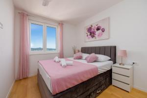扎达尔Stella Maris 2BDR, balcony, sea view, garage, BBQ的一间卧室配有一张带粉色床单的床和一扇窗户。