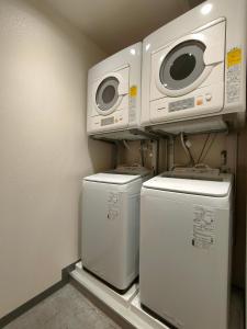 东京Serorin Light Hotel Tokyo的洗衣房配有3台洗衣机和微波炉