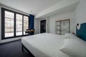 巴黎Beau M Paris的卧室设有一张白色大床和大窗户