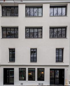 巴黎Beau M Paris的白色建筑的外墙,设有黑窗