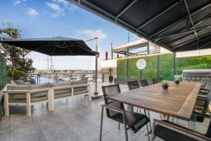 奥克兰THE VIADUCT WATERFRONT LUXURY - Views & Location!的庭院配有桌椅和遮阳伞。