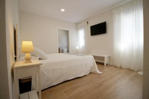 洛萨尔德拉韦拉Casa Verata的白色卧室配有一张床和一张带台灯的桌子