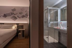 莱昂Hotel NERU con Encanto的一间卧室设有一张床和一个玻璃淋浴间