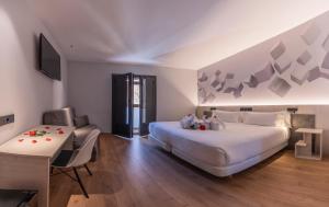 莱昂Hotel NERU con Encanto的一间卧室配有一张大床、一张书桌和电视。