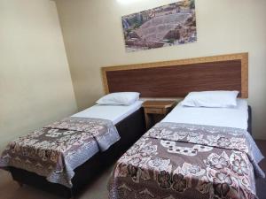 安曼亚洲大酒店的两张位于酒店客房的床,墙上挂着照片