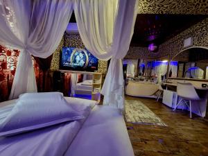 布拉索夫Hotel Boutique Mikaela (Adult Only)的一间卧室配有一张带窗帘的床和电视。