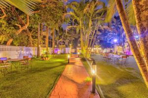 安君纳The Boho, Vagator Beach Goa Near Thalassa的花园在晚上设有桌椅和棕榈树