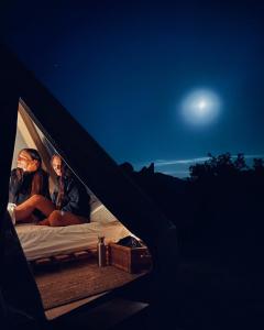 蒙泰蒙阿科La Fattoria dei Sibillini的两人在晚上的帐篷里坐在床上