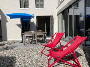 Monte CeneriMarAvilia Apartment - Vicino a Lugano的庭院里设有两把红色椅子和一把遮阳伞