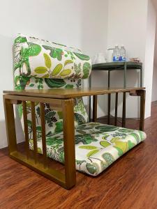 新山Sweet Loft Homestay的铺有木地板,配有带靠垫的绿色白色椅子