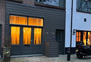 赞德沃特BB The Warehouse Zandvoort的黑色的建筑,窗户上装有橙色窗帘
