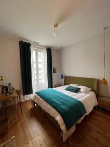 波尔多Maison d'hôtes Alma的一间卧室配有一张床、一张桌子和一个窗户。