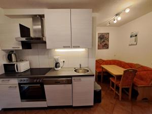 上蒂利拉赫Appartement Haus Gatterer的厨房配有白色橱柜、餐桌和用餐室