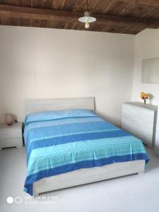 多纳卢卡他Casa vacanze La Meridiana的一间白色卧室,配有蓝色的床和两张梳妆台