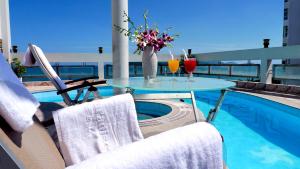 芽庄亚洲天堂酒店的一个带泳池的阳台的桌子和两杯饮料