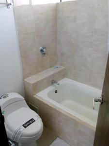 梅尔加Suite Sumapaz Hotel的浴室配有卫生间、浴缸和水槽。