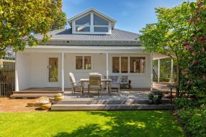 基督城Fendalton Villa - Christchurch Holiday Home的白色的房子,在庭院配有桌椅