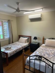 凯恩斯Cheerful city house的一间卧室设有两张床、一盏灯和一扇窗户。