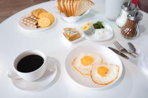 阿克托比Hotel NOMAD的一张带一盘鸡蛋和一杯咖啡的白色桌子