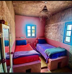 西迪考乌奇Hippie Chic Room 2的配有色彩缤纷的墙壁和窗户的客房内的两张床