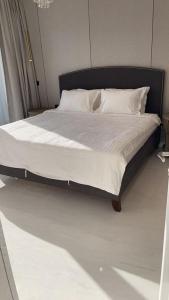 吉达Damac Al Jawharah Tower Apartments的一张带黑色框架和白色床单及枕头的床