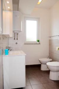 拉布Apartman Maria 1的白色的浴室设有卫生间和窗户。