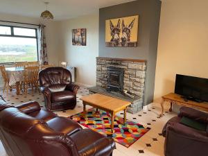 奎尔蒂Quilty Holiday Cottages - Type B的客厅配有皮革家具和壁炉