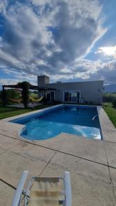 萨尔塔Aires de Ensueño - Casa de Campo的房屋前带两把椅子的游泳池